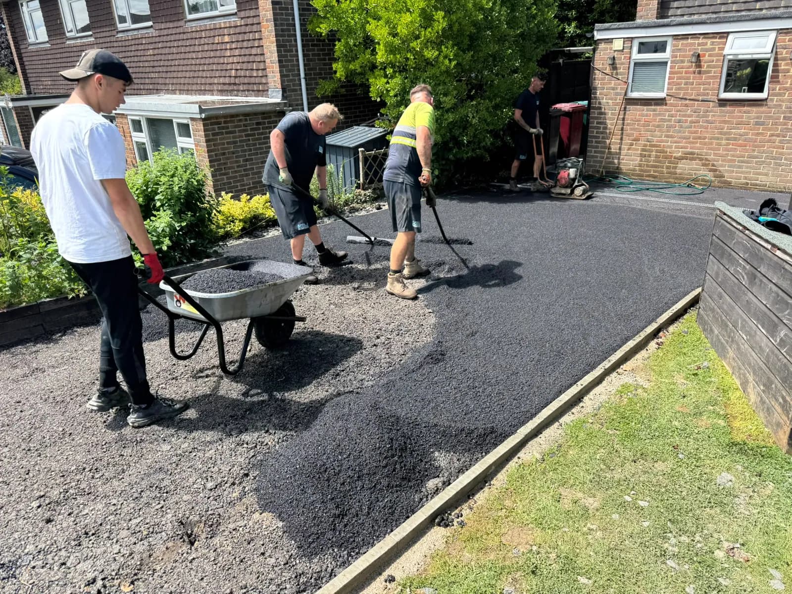 Surfacing crew raking out hot tarmac on a driveway